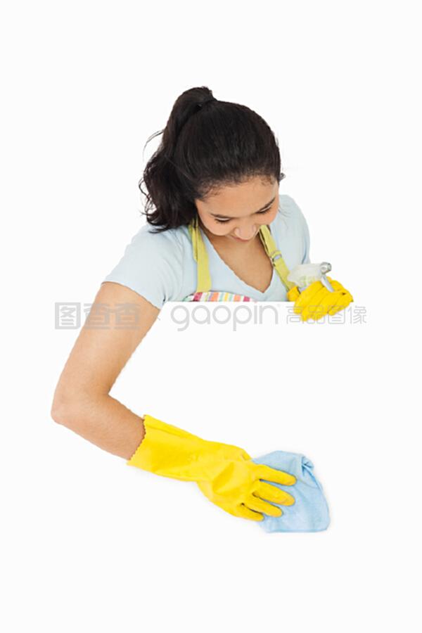 戴着手套、面带微笑的女人在清洗白色表面